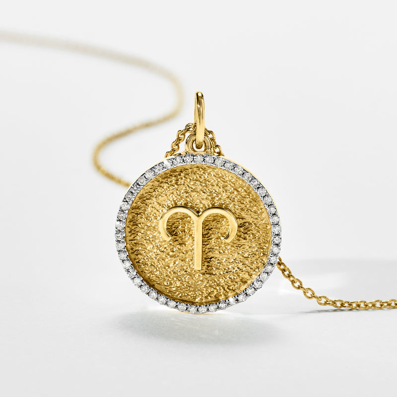 Round gold-tone zodiac pendant necklace with diamond-like pave rim and engraved center glyph