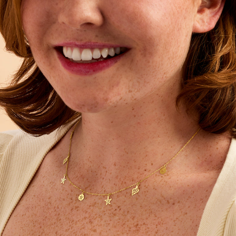 Yellow gold sea life necklace with small starfish and shell stations, close-up