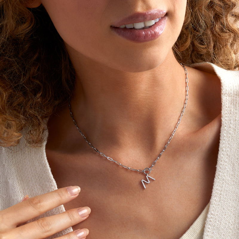 Sterling silver diamond initial pendant necklace worn with paper-clip link chain and toggle