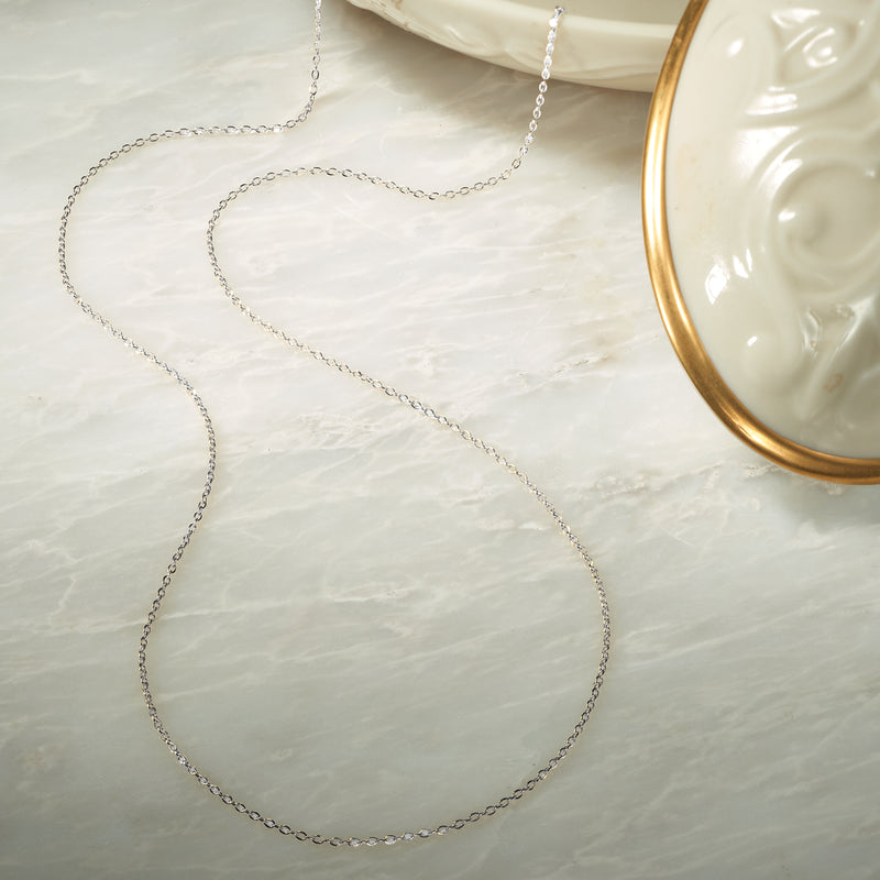 Sterling silver cable-chain necklace laid flat, fine round links