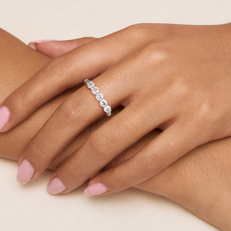Five-stone diamond ring on finger in 14kt white gold with five round prong-set stones