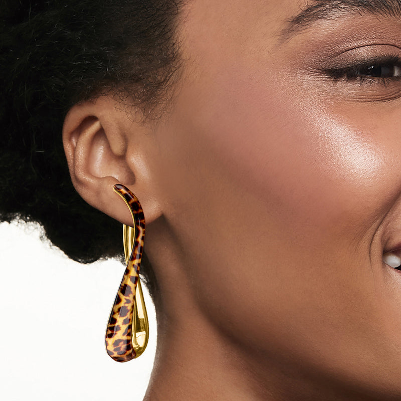 Leopard-print enamel twisted hoop earrings on model's ear, gold-tone finish