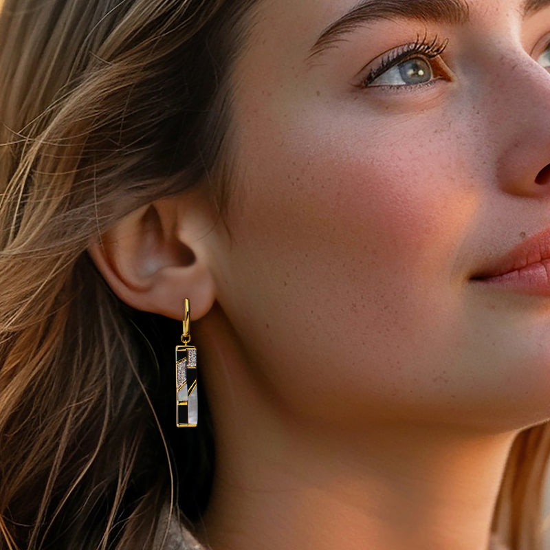 Gold drop earrings on model: black and white striped rectangular dangles with sparkle