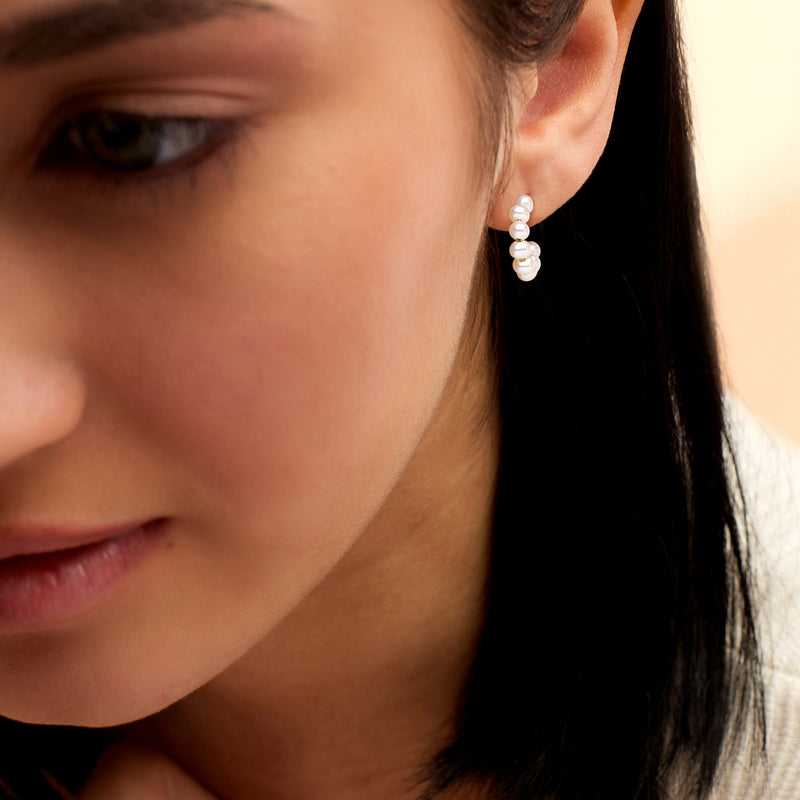 Cultured pearl C-hoop earrings in 14kt yellow gold with white beads, on ear