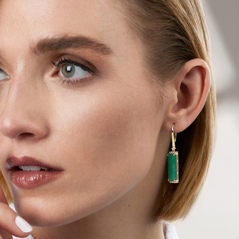 Gold leverback drop earrings on model, emerald-green rectangle with white stone borders