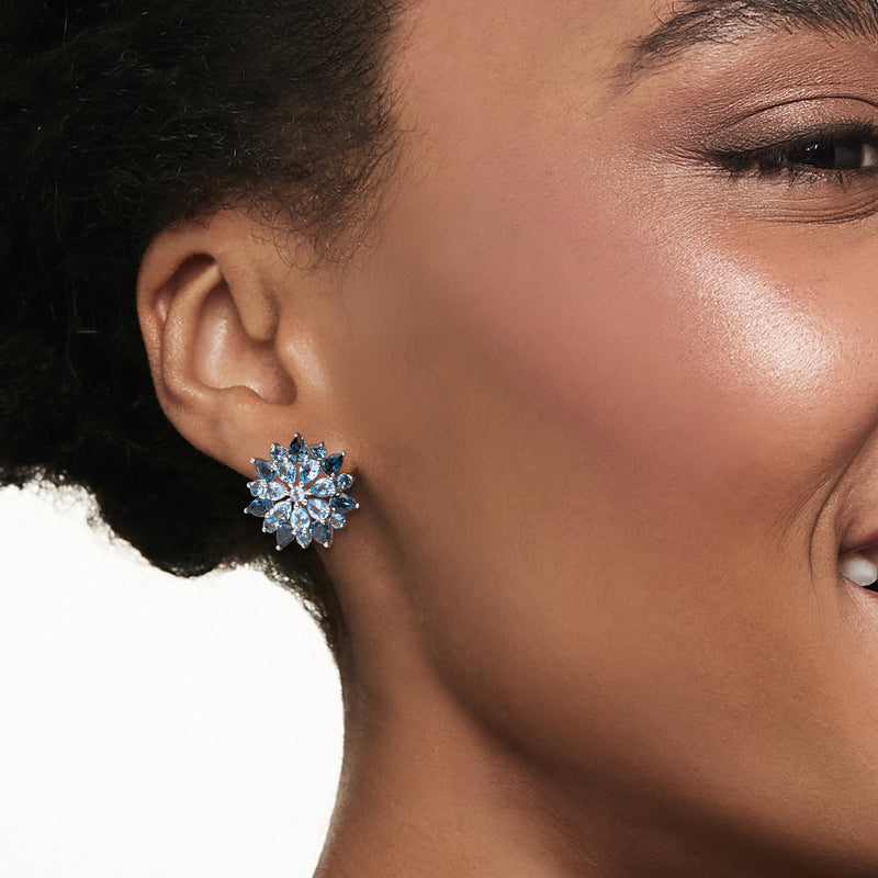 Sterling silver post earrings worn on ear, blue floral gemstone cluster with round center