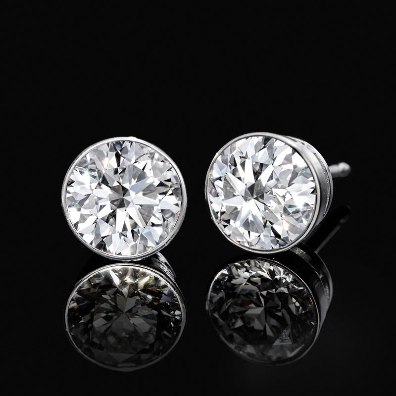 Bezel-set round lab-grown diamond stud earrings in 14kt white gold, angled view pair.