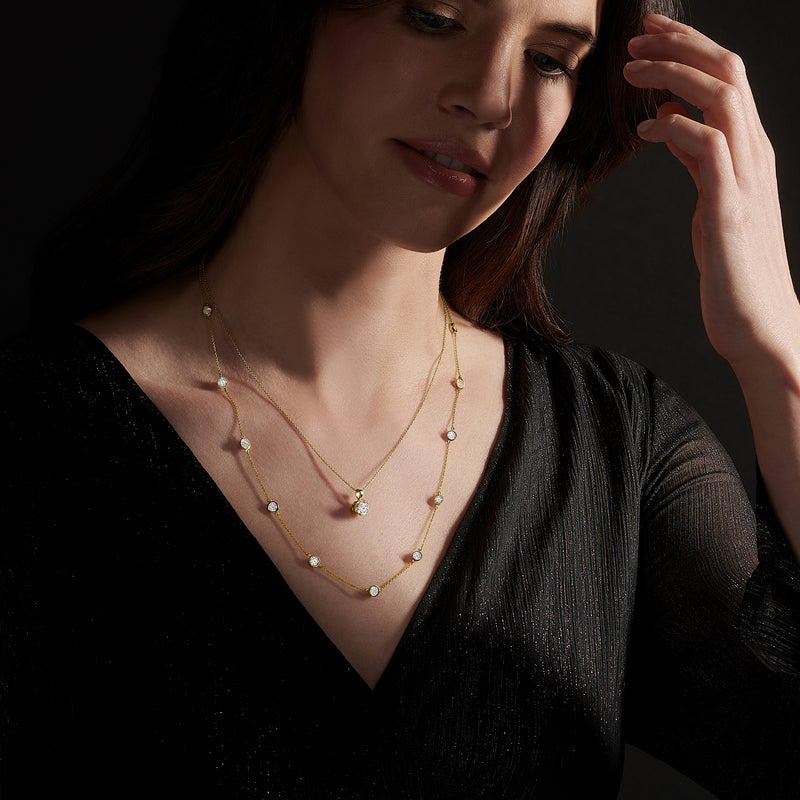Gold station necklace with small round diamond-like stations, worn on model