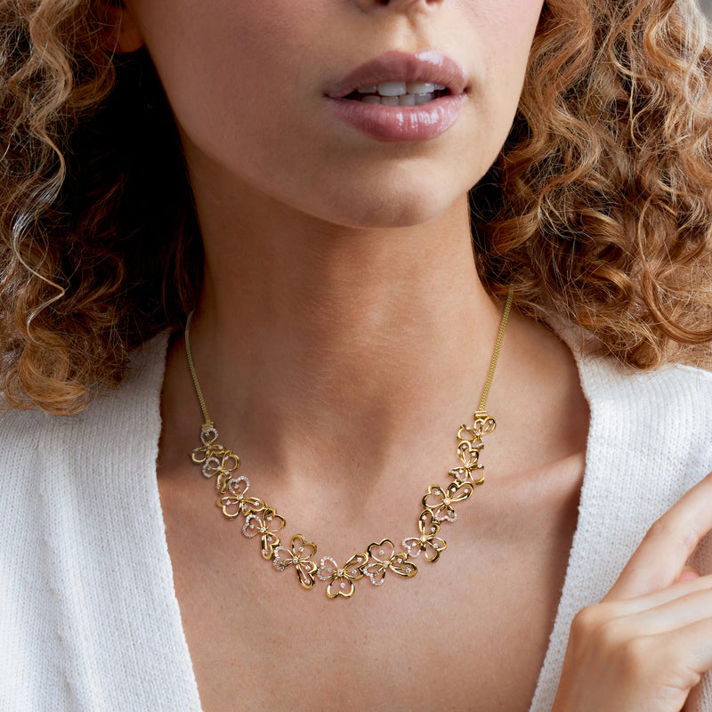 Gold-tone floral diamond necklace worn close-up with linked clover flower motifs