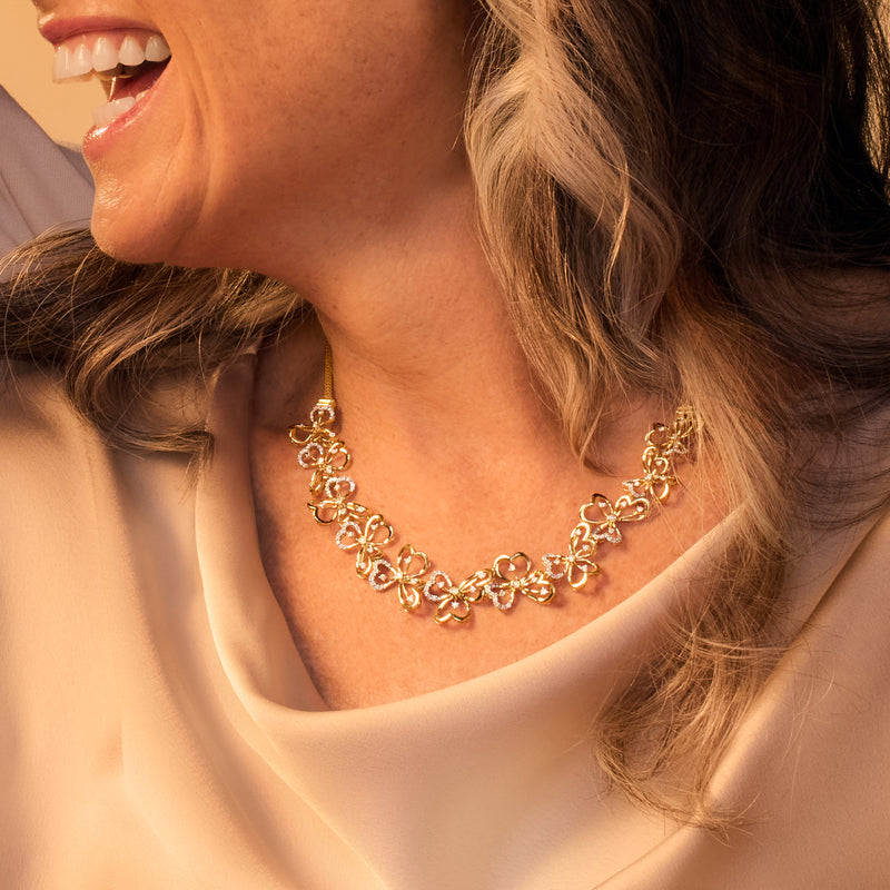 Gold-tone floral diamond necklace on model neckline with clustered clover flower motifs