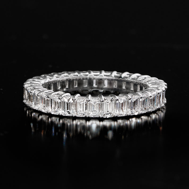 Close-up top view of 14kt white gold eternity band with emerald-cut diamond settings