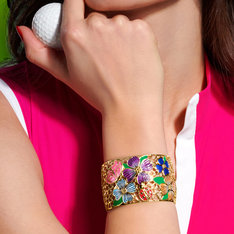 Multicolor enamel floral cuff bracelet in gold tone worn on wrist, hinged lattice design