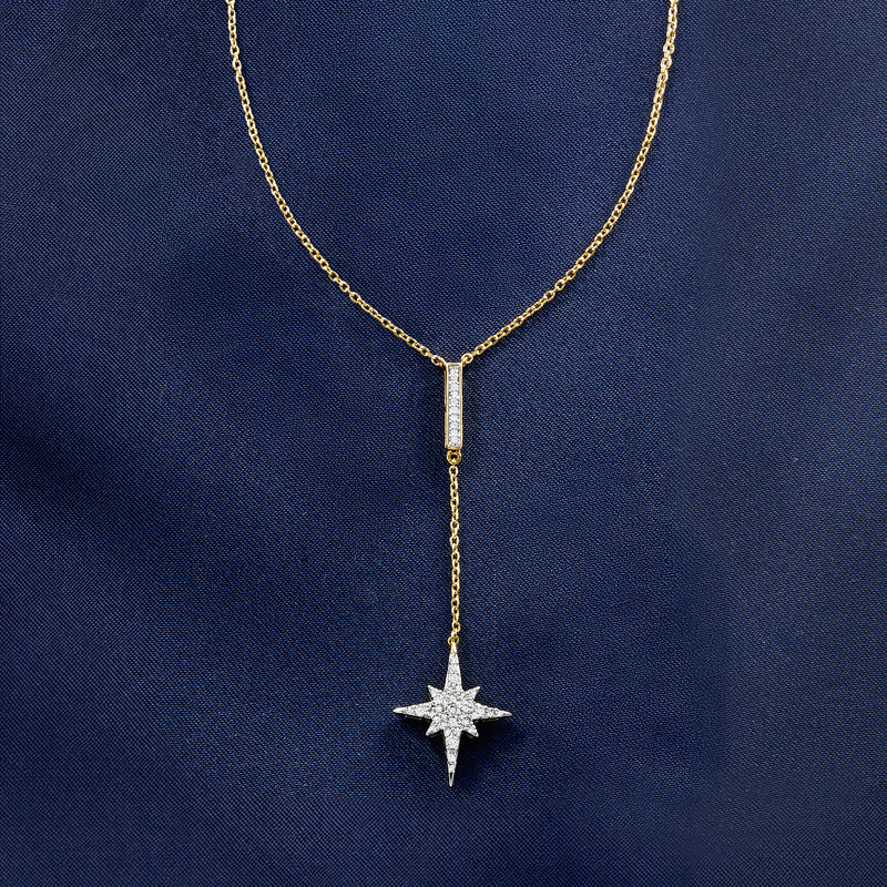 Gold Y-necklace pendant close-up with star charm and vertical baguette-style stone