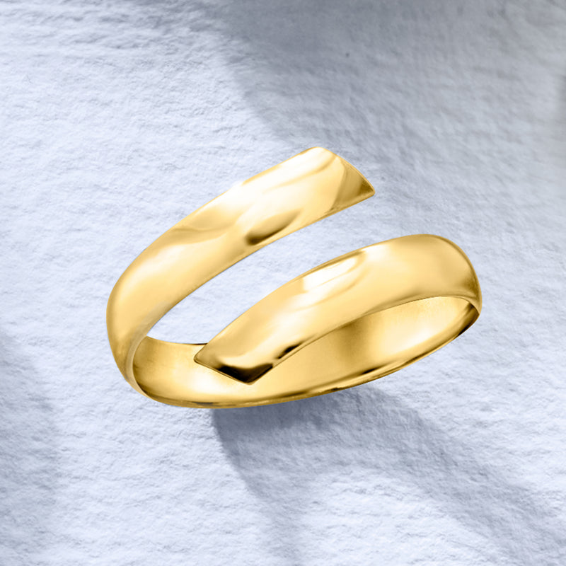 Yellow gold bypass ring shown at angle, smooth oval top and open gap