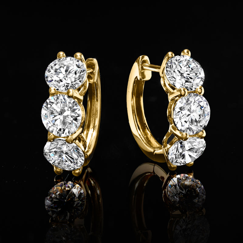 Yellow gold huggie hoop earrings with three round diamonds, side view