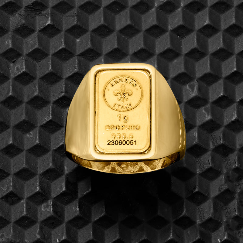 Yellow gold square-stamped signet ring with fleur-de-lis, “19 ORO PURO 999.9” detail.