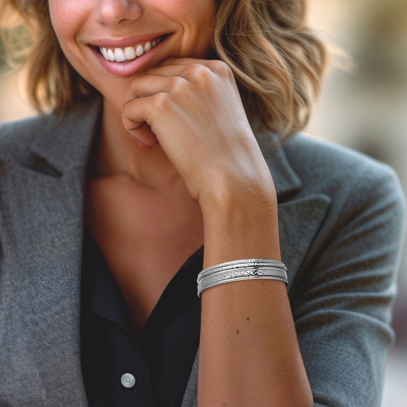 Five sterling silver bangles on wrist, mix of smooth bands and textured patterns