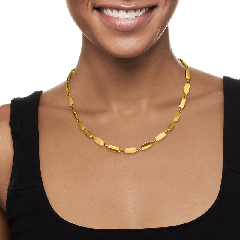 Yellow gold bar-link necklace worn with short links along the collar