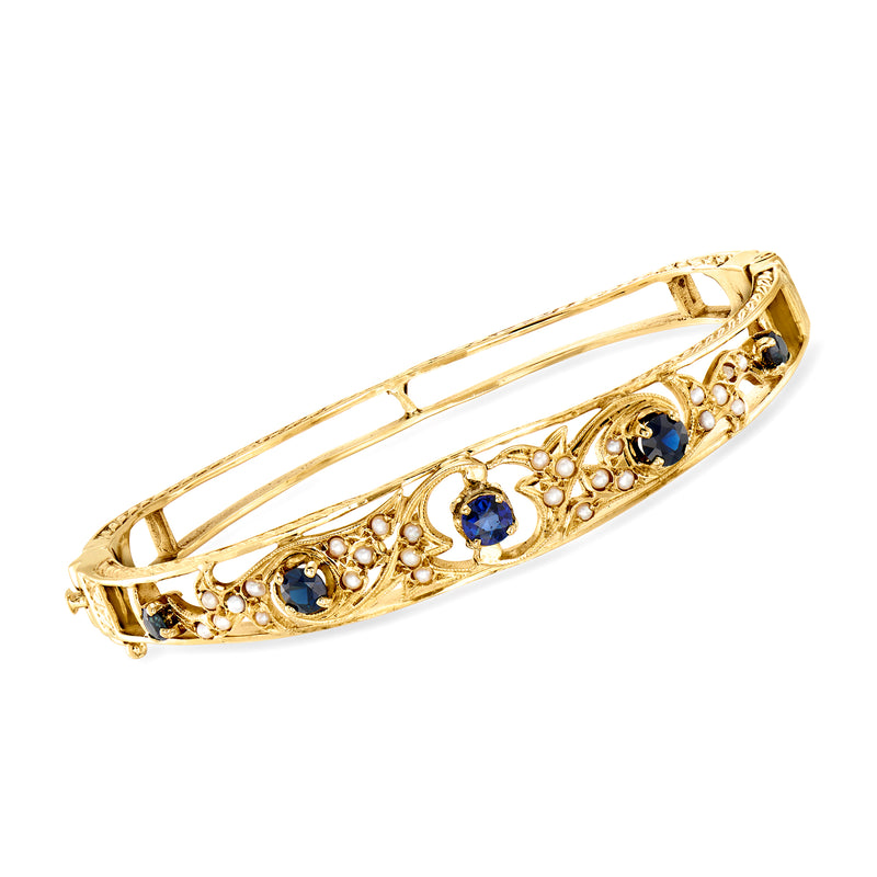 Yellow gold bangle bracelet with blue sapphire stones and small seed pearls.