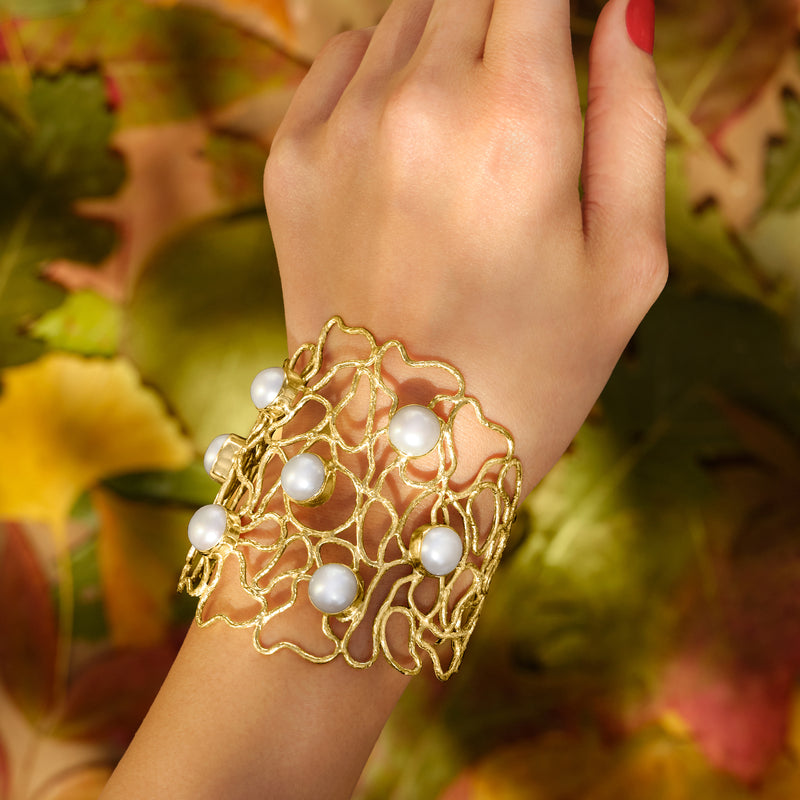 Gold openwork cuff bracelet with white pearls on wrist, 18kt gold over sterling