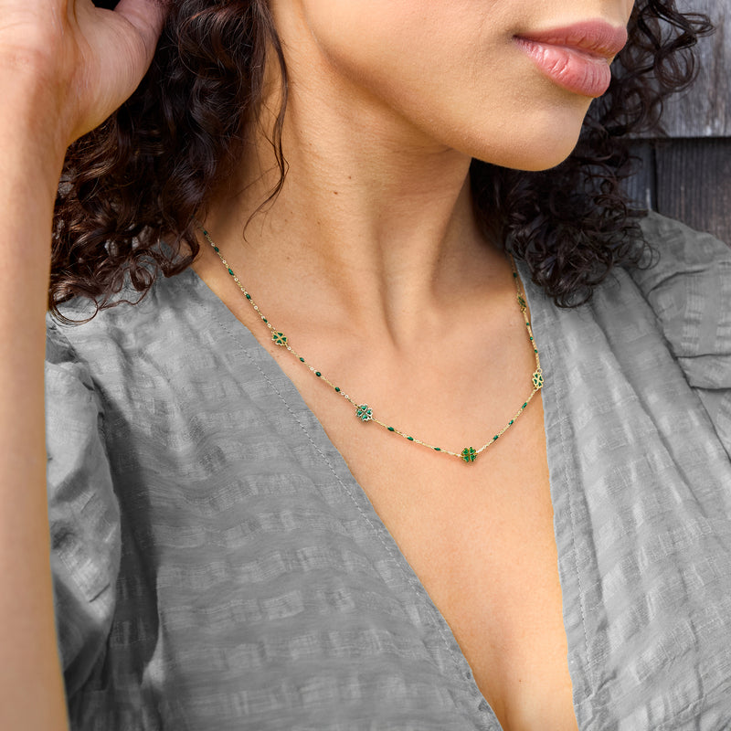 Yellow gold clover station necklace with green enamel on model neckline