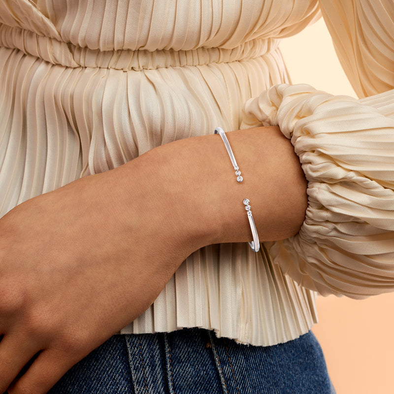 Sterling silver diamond cuff bracelet worn on wrist, bezel-set round stones