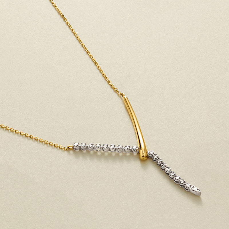Two-tone Y-necklace detail: gold V with round diamond row and dangling drop