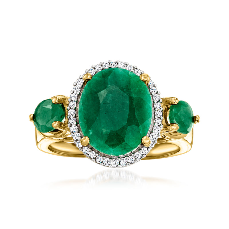 Oval emerald ring with diamond halo, flanked by two green stones, gold setting