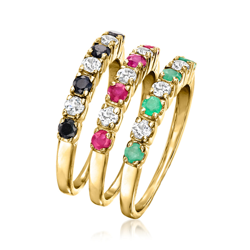 Three slim gold-tone rings with black/white, pink, and green gemstone bands.