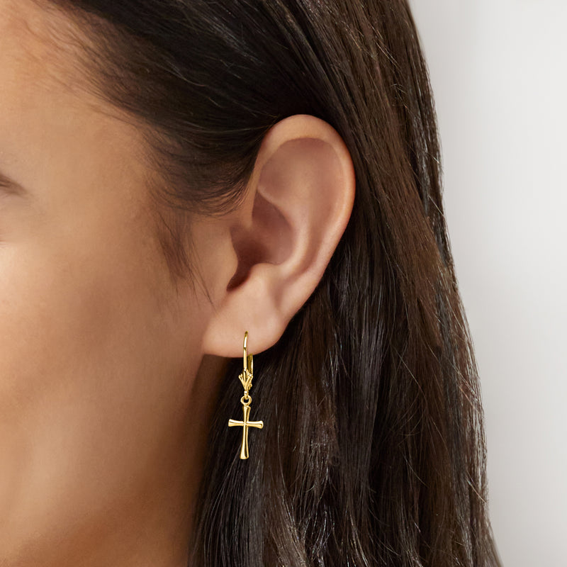 Yellow gold cross drop leverback earrings on ear, small dangling cross