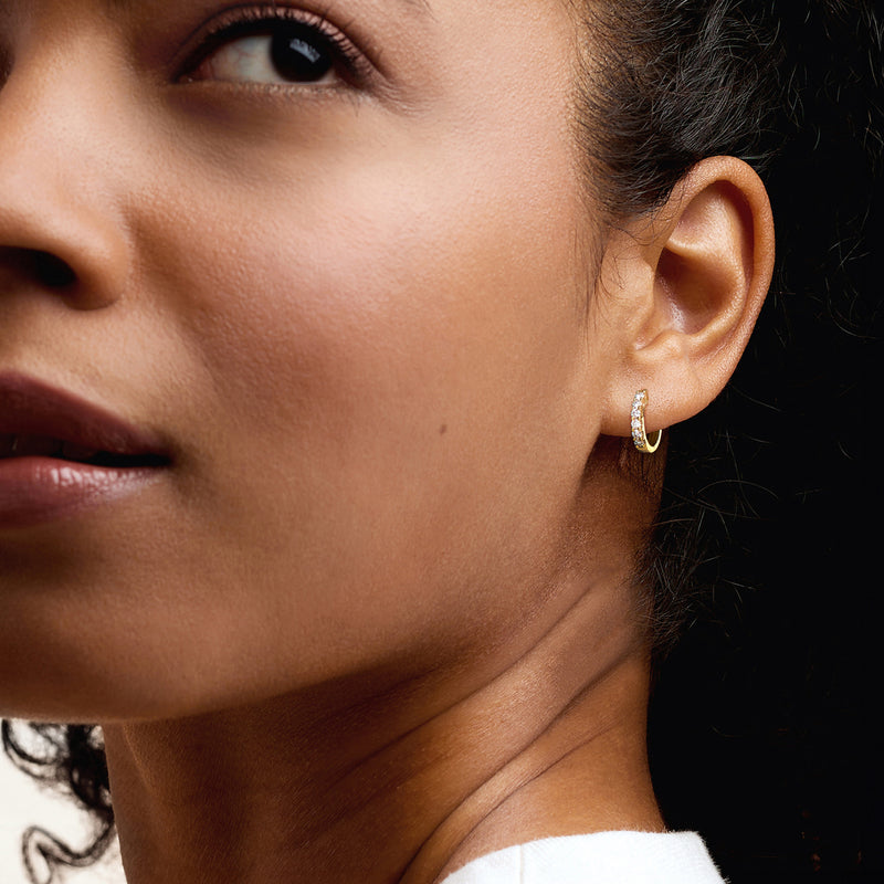 Small gold hoop earrings with round diamond accents near the front