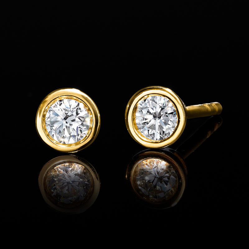Lab-grown diamond stud earrings with round bezel-set stones, gold bezel and posts.