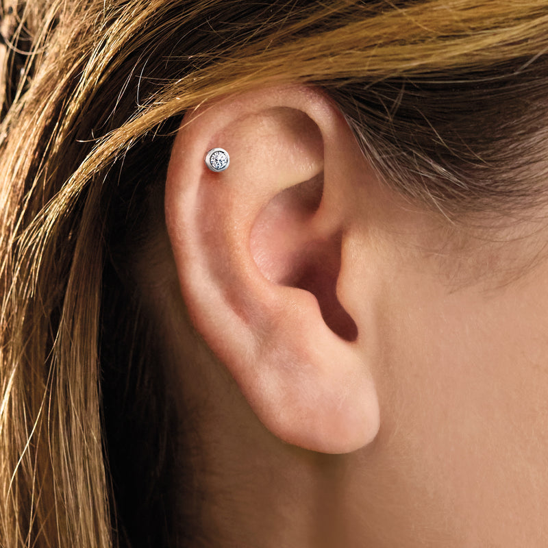 Sterling silver diamond stud earrings on ear, small round bezel-set stone