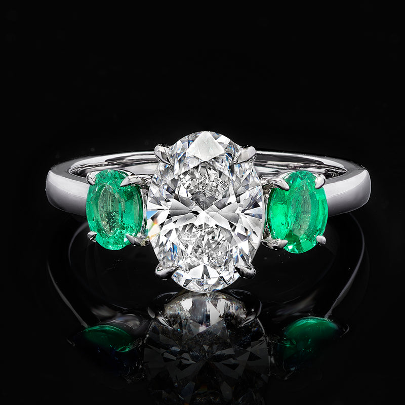 14kt white gold diamond ring with large round center diamond and 2 green emerald stones