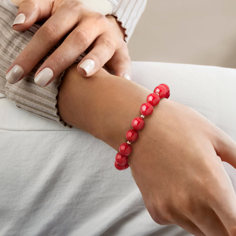 Red coral bead stretch bracelet on wrist with yellow gold spacer beads and round beads