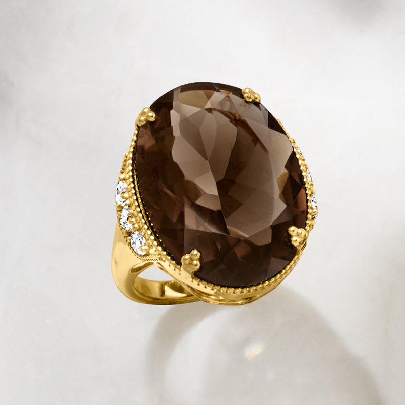 Gold-tone oval smoky quartz ring with textured bezel and white zircon accents along band.