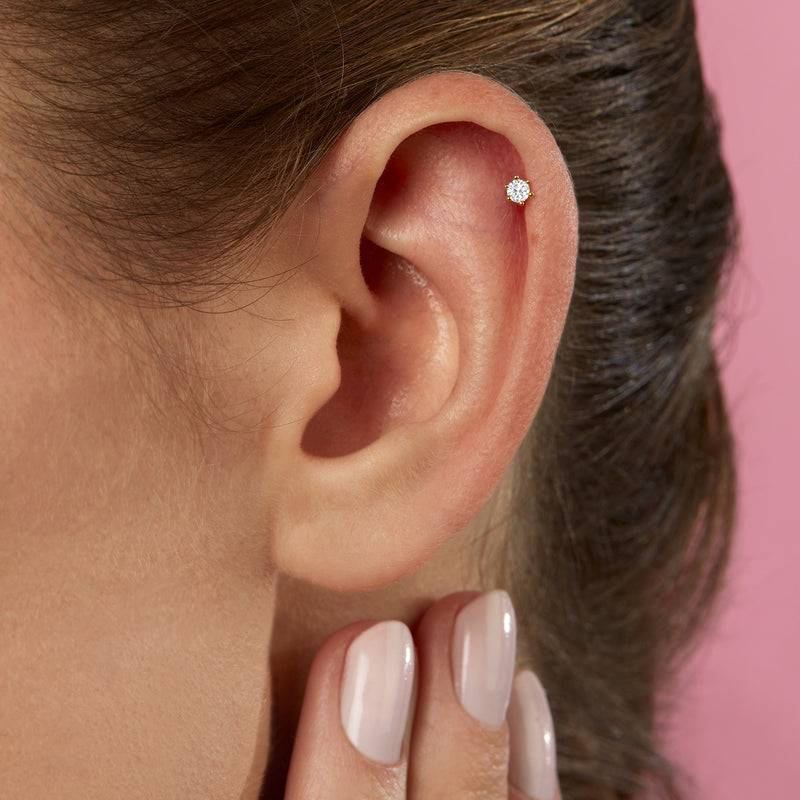 Close-up of 14kt yellow gold diamond stud earring on ear