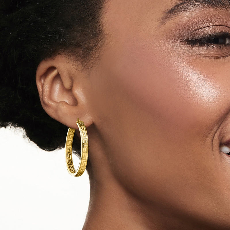 Yellow gold Greek key hoop earrings, close-up on ear, polished oval frame