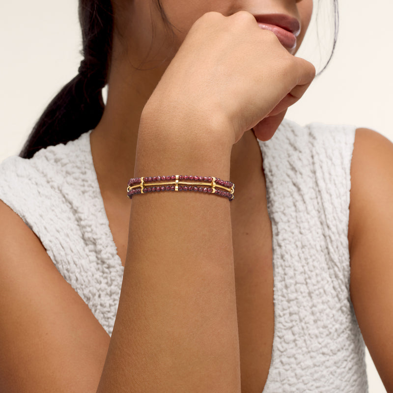 Garnet bead bracelet in gold over sterling worn on wrist with multiple strands