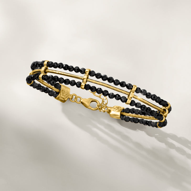 Black beaded bracelet with slim gold center bar and toggle clasp, layered rows