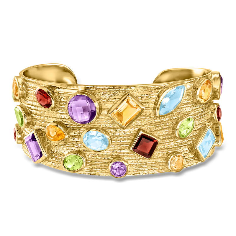 Gold cuff bracelet with assorted colorful gemstones, open top setting.