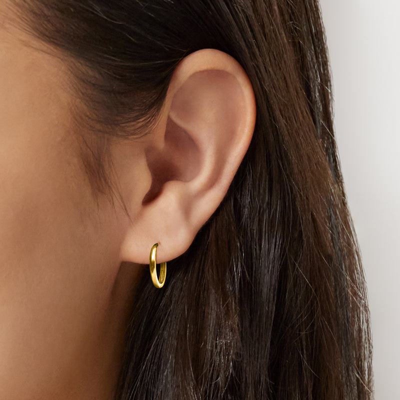 Petite huggie hoop earrings on ear, small rounded 10kt yellow gold loop