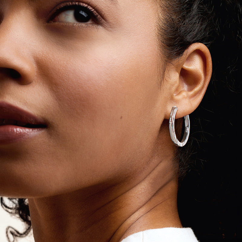 Hammered sterling silver hoop earrings on ear, rounded profile and shine