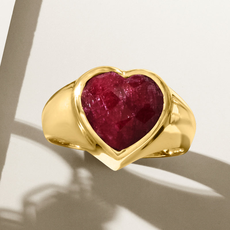 Gold ring with heart-shaped ruby gemstone in raised bezel setting