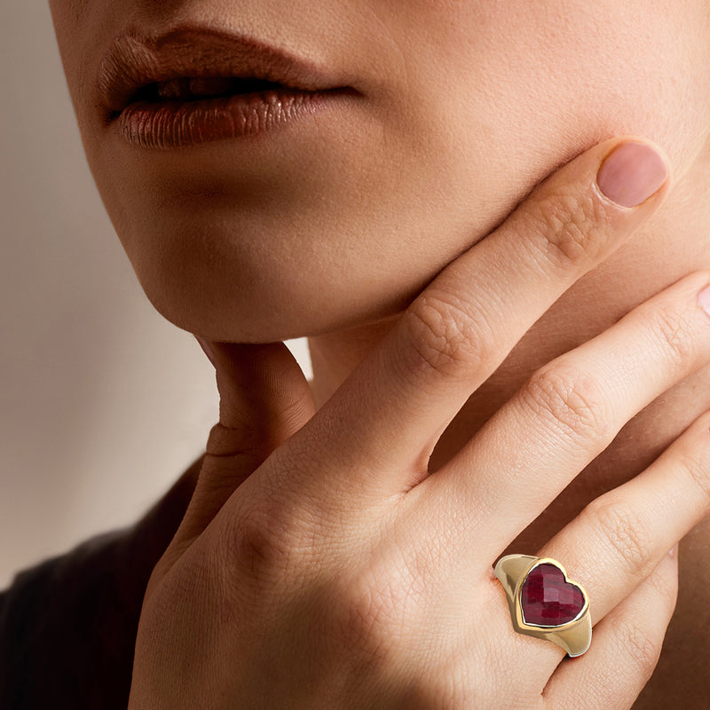 Gold heart ruby ring on finger with red gemstone heart bezel