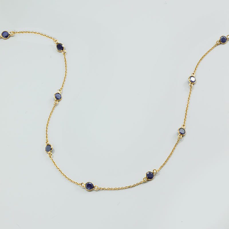 Close-up view of gold over sterling sapphire station necklace with blue oval stones