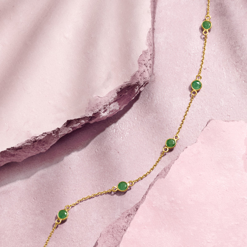Gold station necklace with evenly spaced oval green gemstones on a fine chain