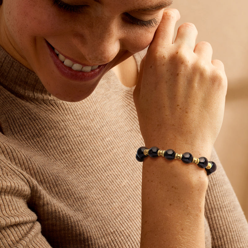 Onyx bead bracelet on wrist, dark round beads with gold-tone spacers and toggle