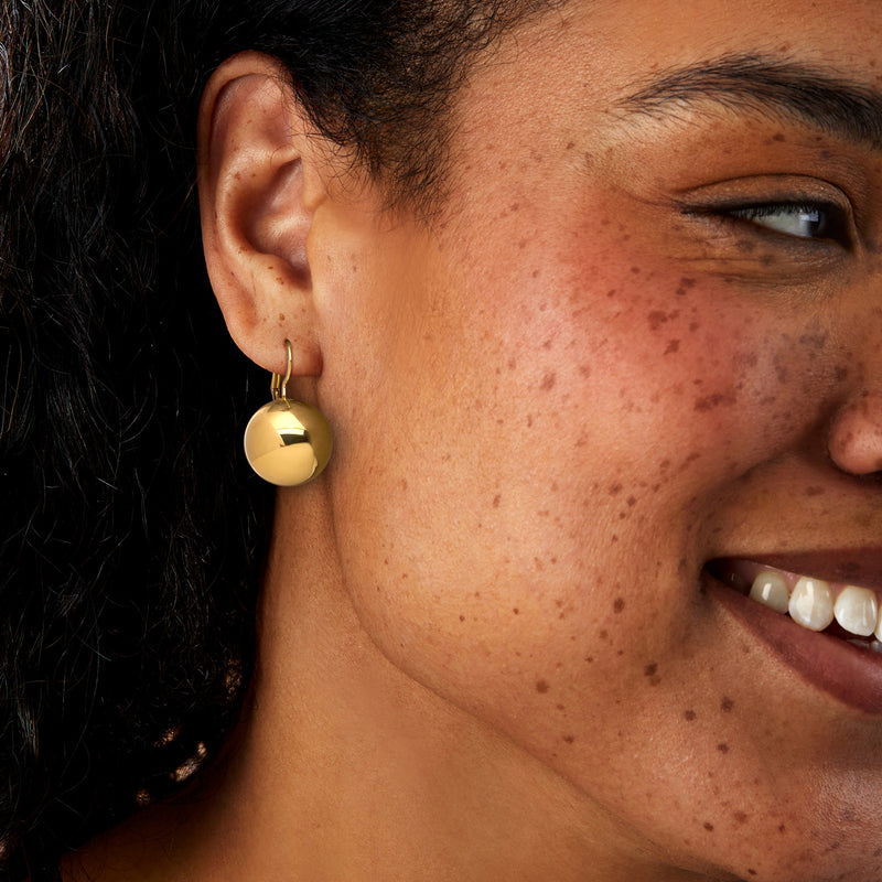 Gold ball drop earrings on ear with leverback, polished round drops