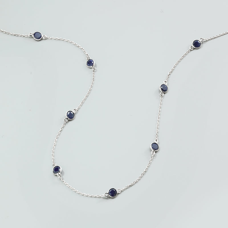 Sterling silver sapphire station necklace laid flat with oval blue station stones